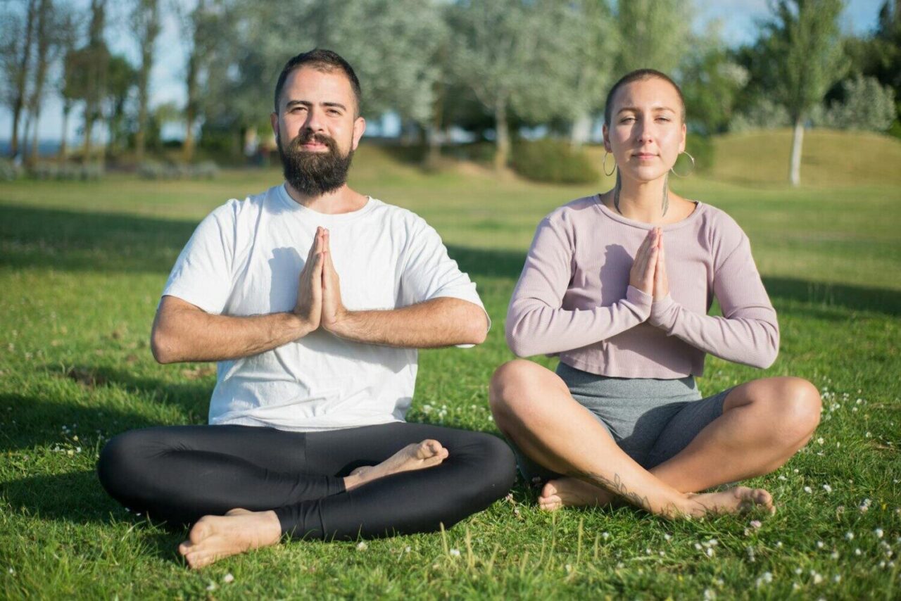 Serene outdoor meditation with a couple sitting cross-legged in a Portuguese park.